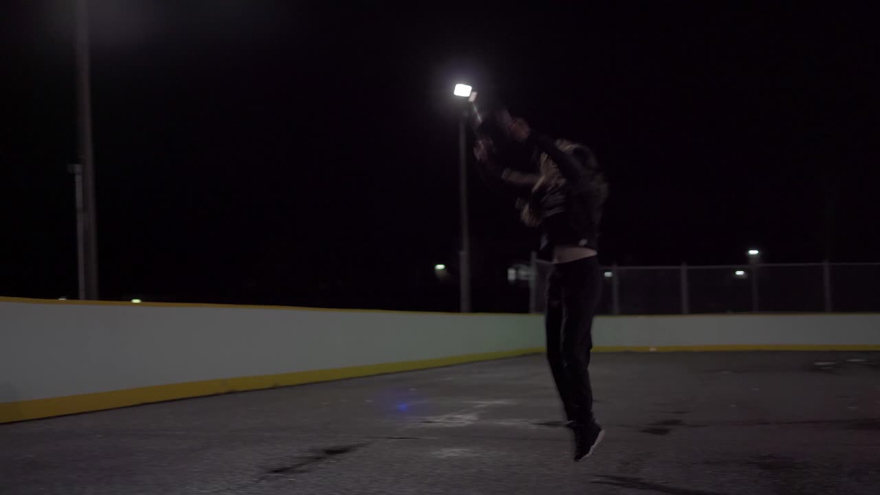 Teenage girl dribbles ball then shoots it at the net at an outdoor court with lights in the dark
