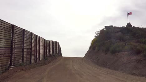 an empty road along the us mexican border with an american flag flying in the distance