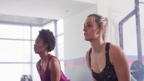 video de dos mujeres diversas trabajando en un gimnasio haciendo columpios de kettlebell al unísono