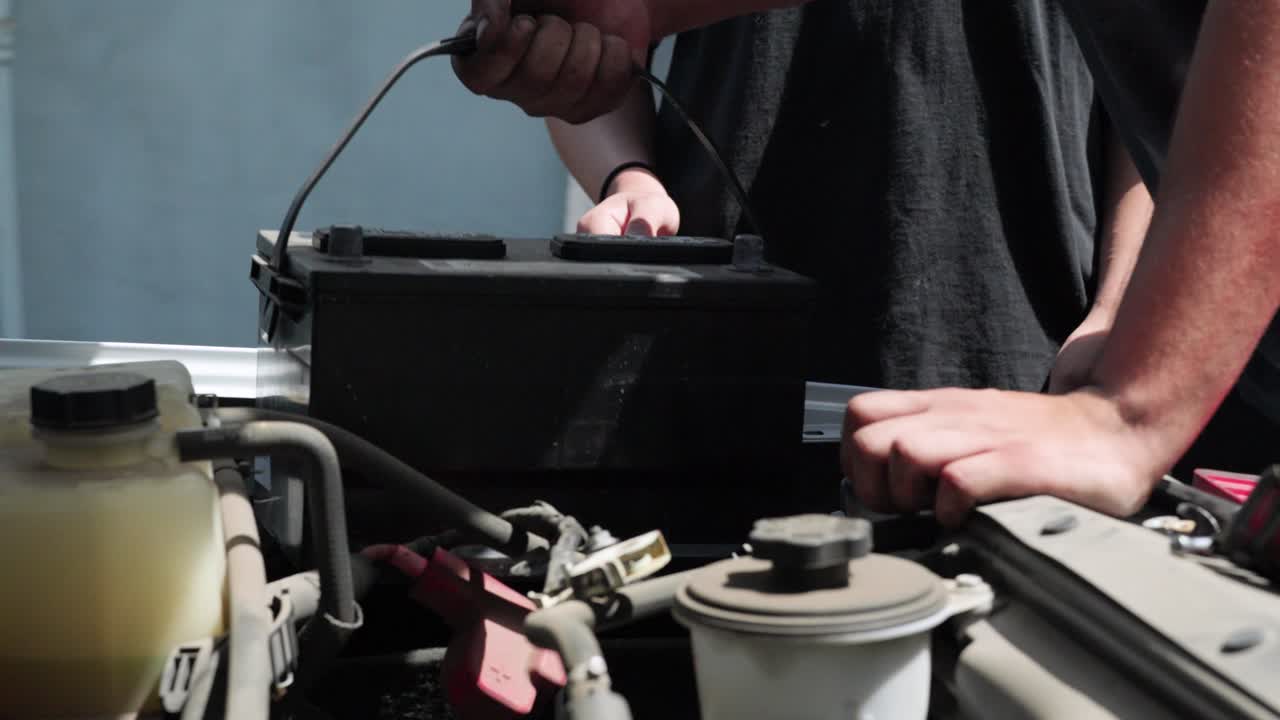 トラックの自動車バッテリーを交換する整備士たち。