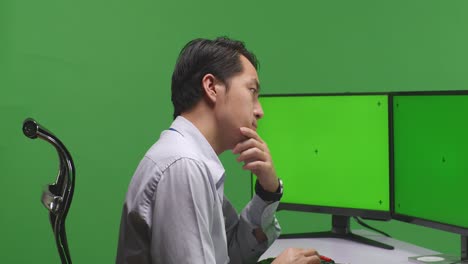 man working at a computer on a green screen