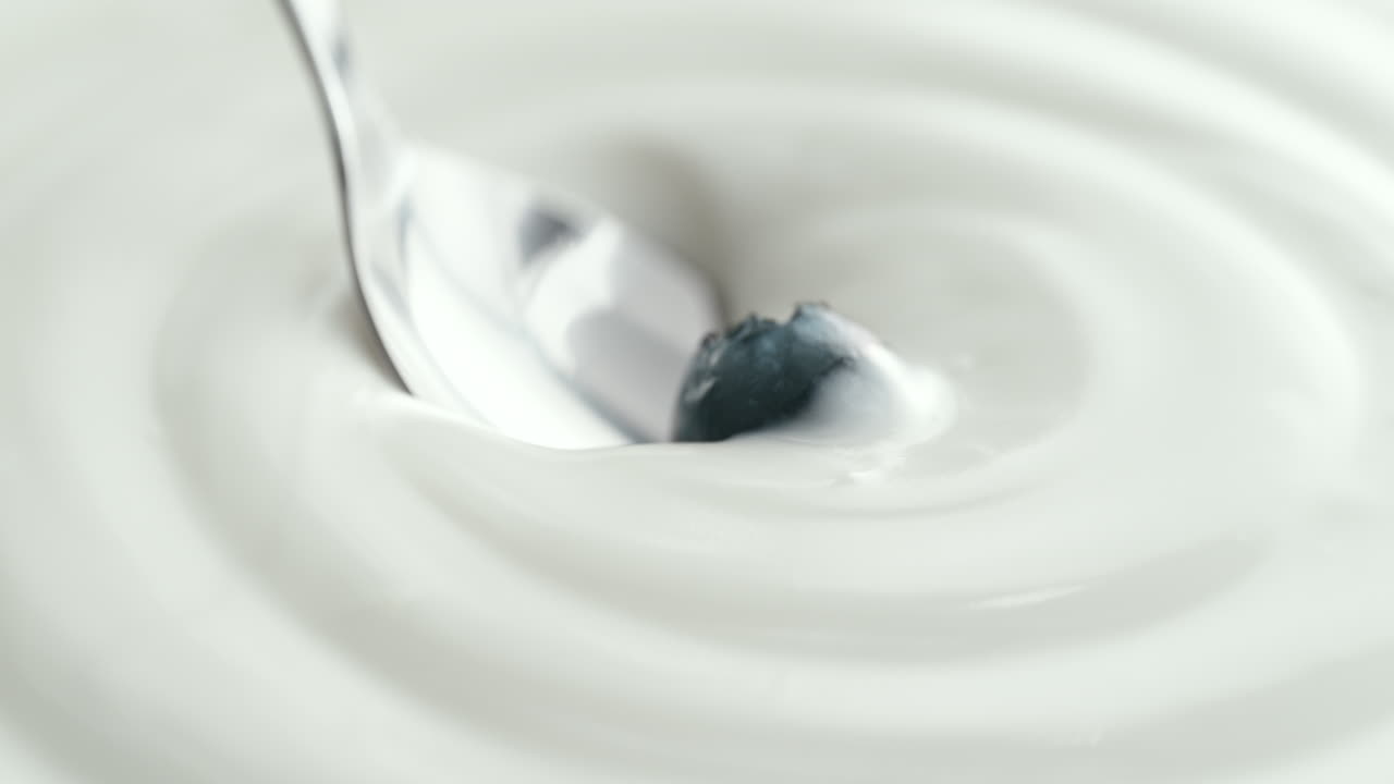 Blueberry Scooped with Silver Spoon from Creamy Thick Yogurt in Macro and Slow Motion