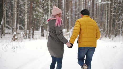 A-young-and-beautiful-couple-is-having-fun-in-the-park,-running-and-holding-hands.-Valentine's-Day-and-love-story-concept.-Winter-season.