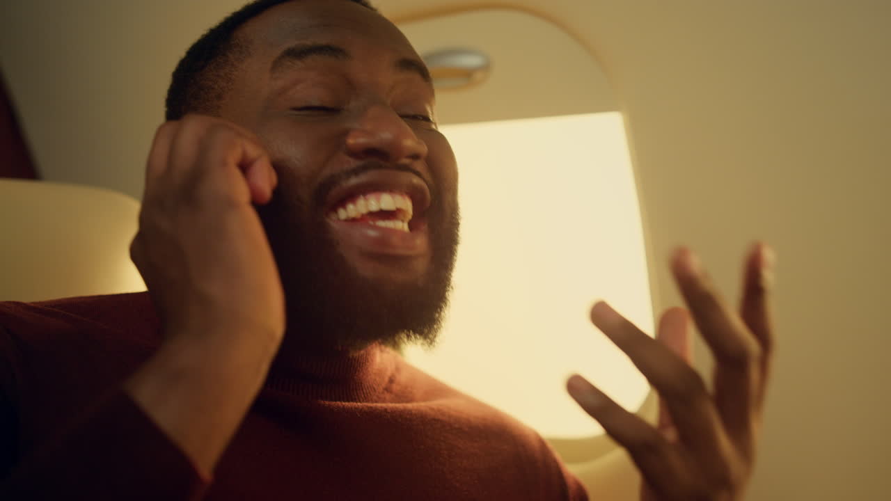 Uomo gioioso che chiama un amico in aereo in primo piano. Felice afroamericano che discute.