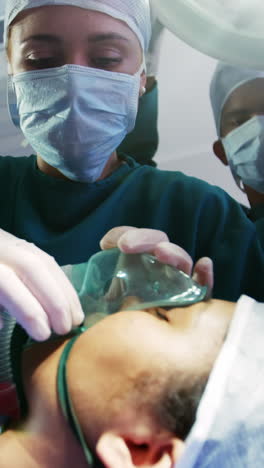 surgeon putting oxygen mask on patient in operation room