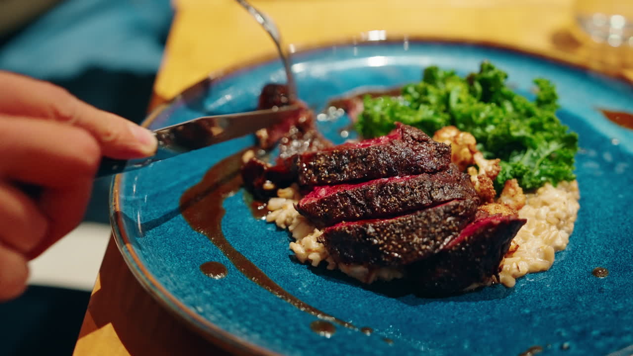 Close up shot of meat course with vegetables being cut with cutlery at the restaurant. Culinary experience. Vibrant healthy food.