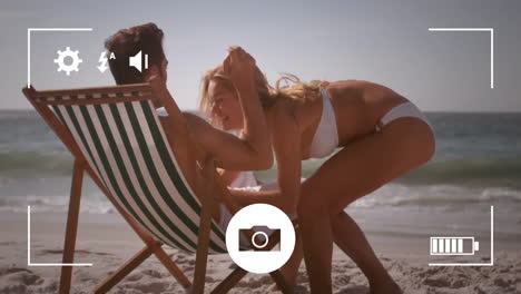 animación de la pantalla de la cámara sobre una pareja caucásica corriendo y acostada en una cama de sol en la orilla del mar