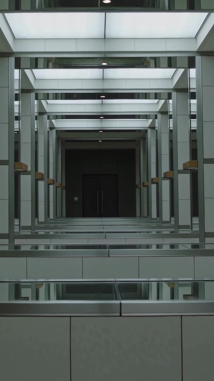 Vídeo vertical: Câmera com zoom centralizando no corredor do átrio, mostrando simetria, claraboia e porta escura