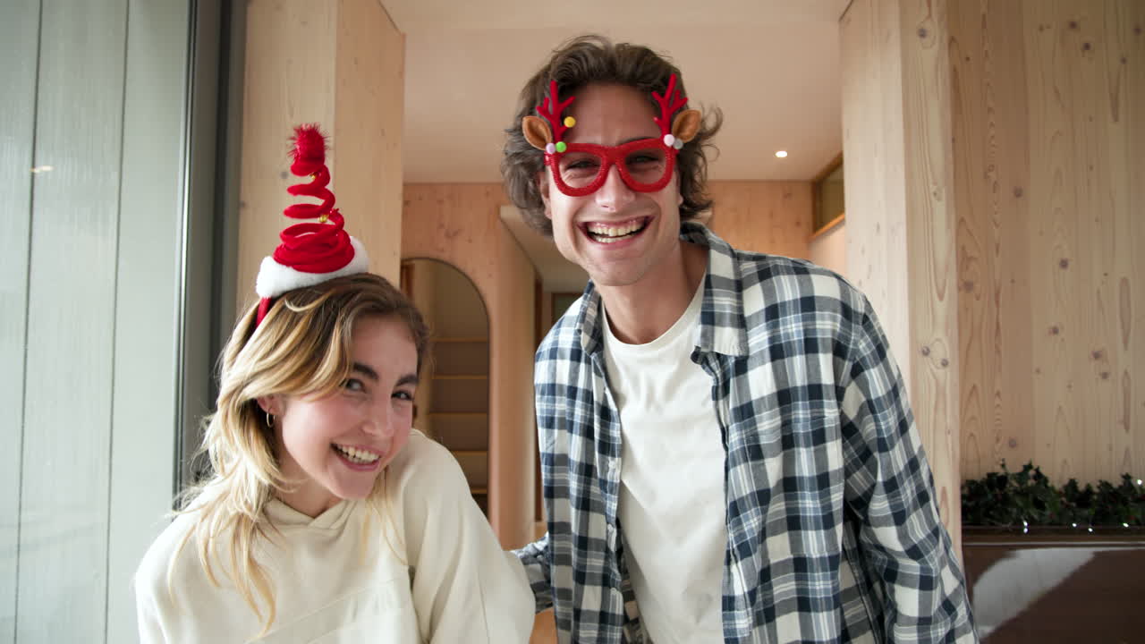 Playful couple wearing festive accessories enjoying Christmas fun at home