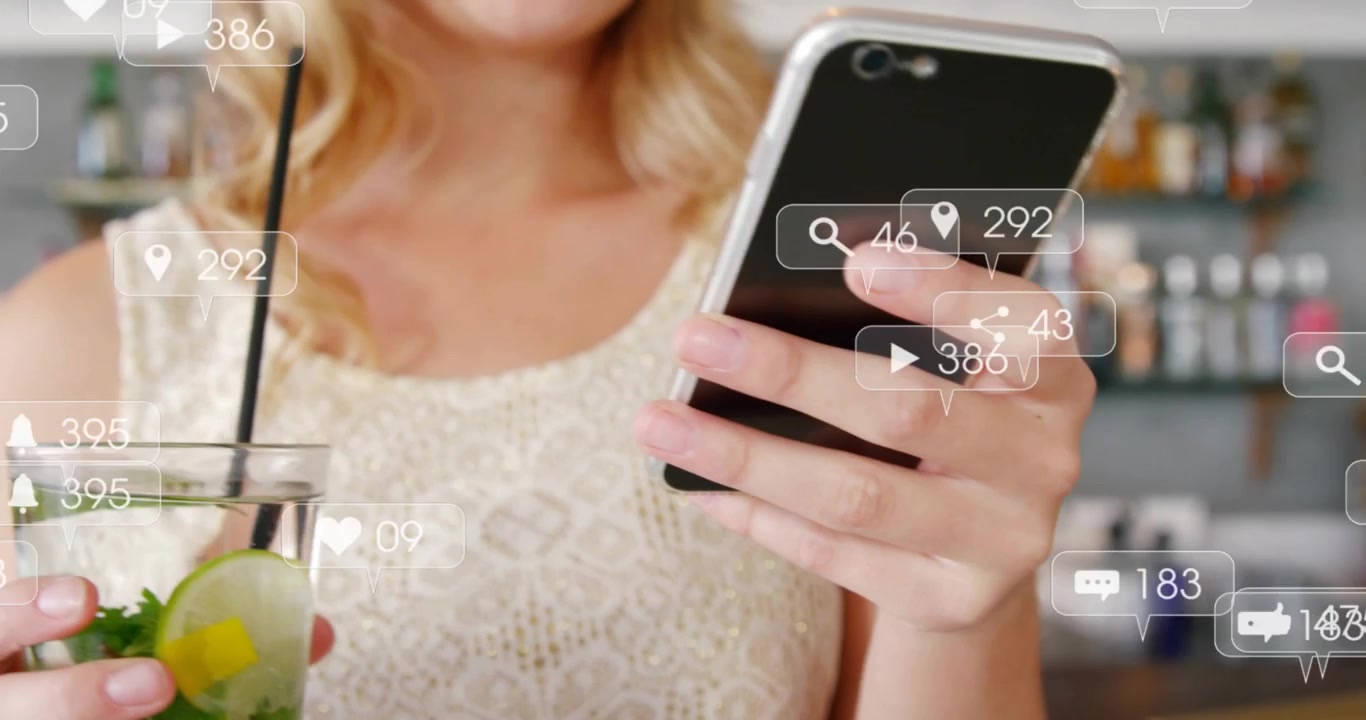 バーでソーシャルメディアの通知が表示されたスマートフォンを使用する女性