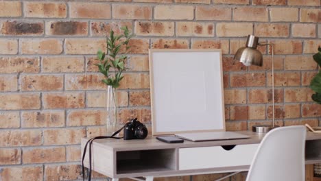 Wooden-frame-with-copy-space-on-white-background-with-plant-on-desk-against-brick-wall