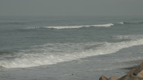 Un-Surfista-Rema-En-Una-Playa-De-La-Reserva-Natural-Estatal-De-Torry-Pine-En-San-Diego,-California