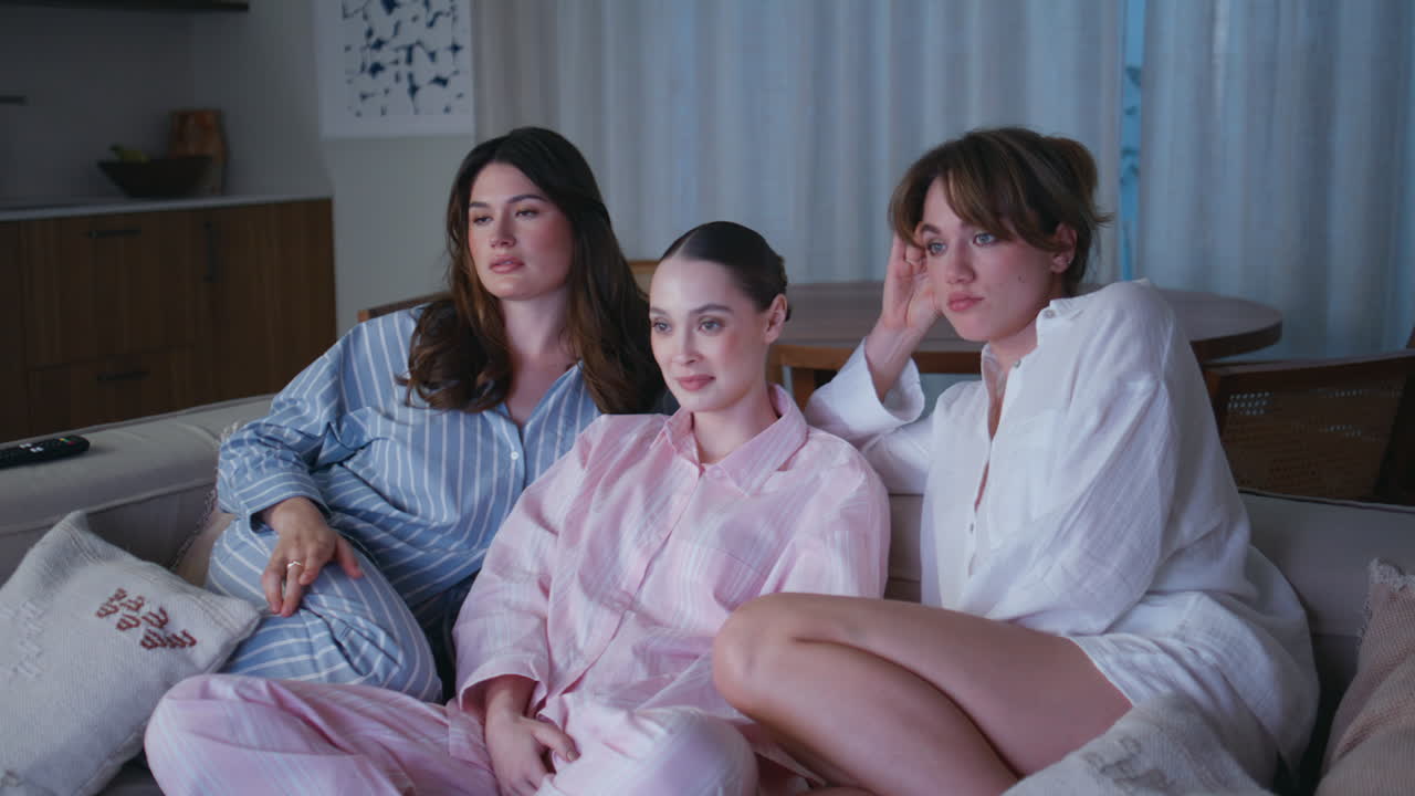 Group women watching melodrama on TV at home sofa closeup. Three female friends