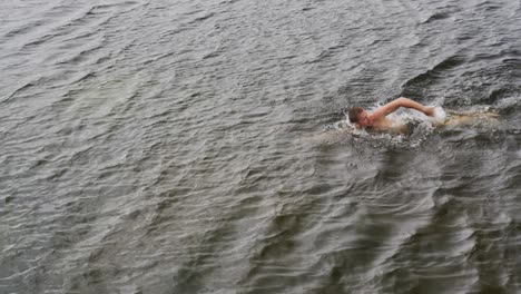 caucasian man having a good time on a trip to the mountains, wearing swimming trunks and swimming in