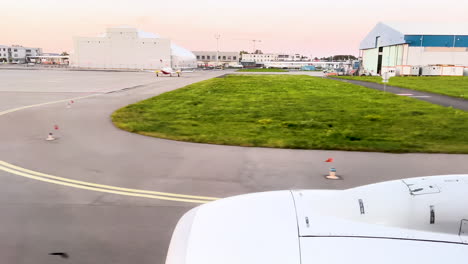 view from airplane window on the tarmac at dusk, with airport buildings and directional arrow on ground