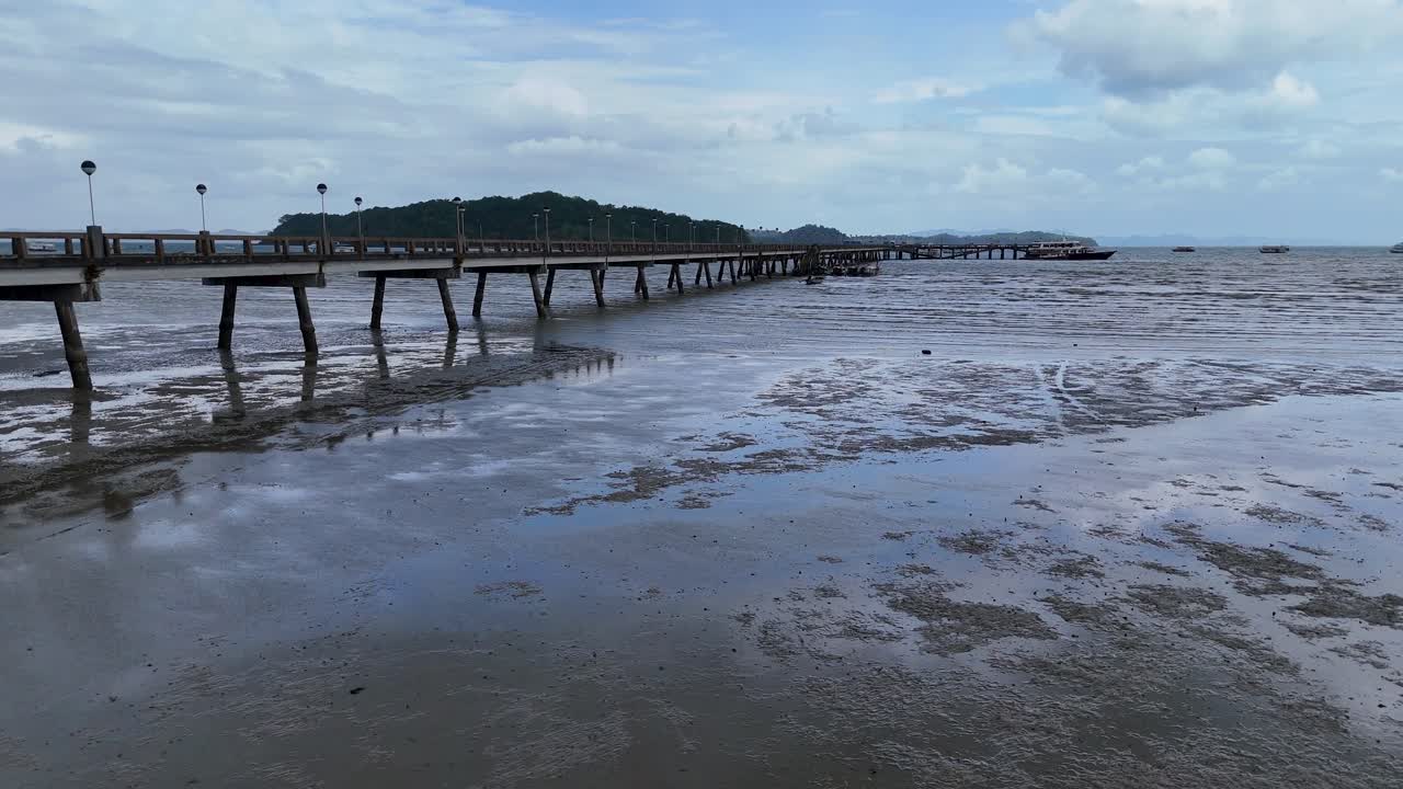 Aerial footage of a tranquil pier in Phuket, Thailand, showcasing serene waters and a cloudy sky captured by a drone