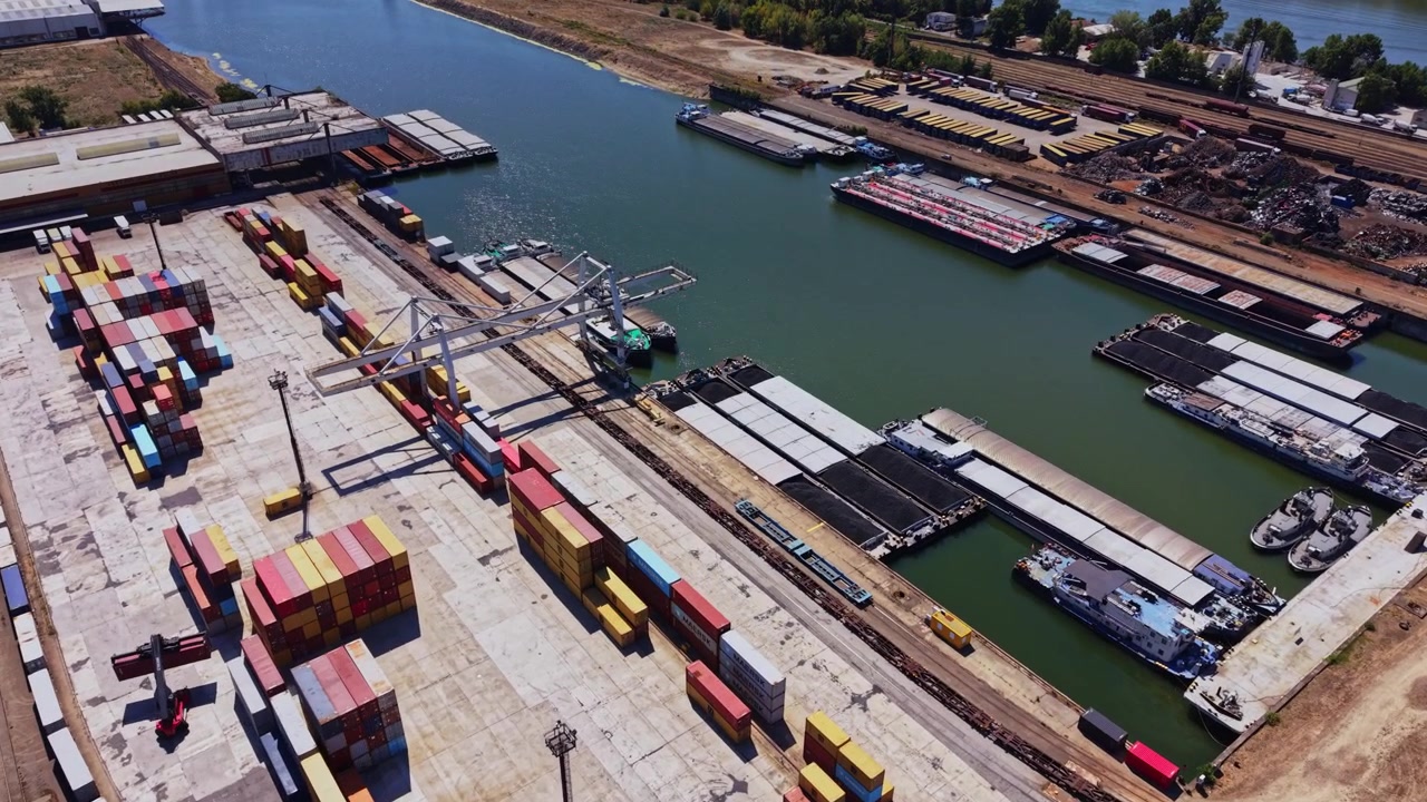 Container yard by the river with trucks and ships in action during daytime