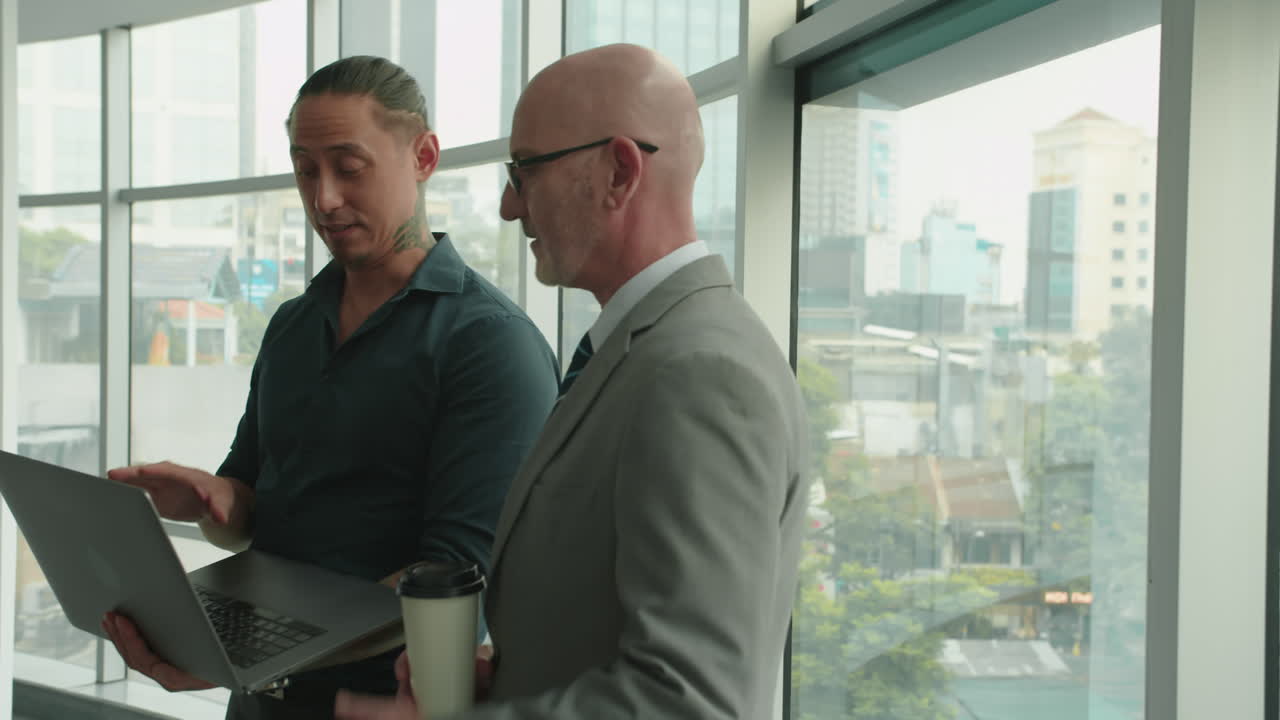 CEO and Manager Analyzing Statistics Using Laptop at Office