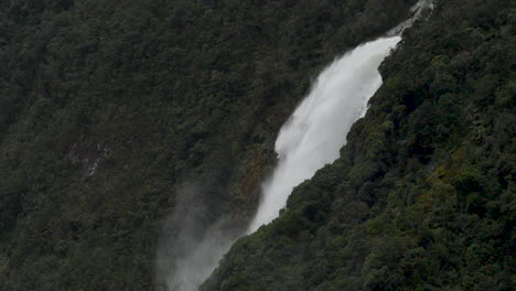 slow motion shot of a large waterfall in milford sound after a rain storm - piopiotahi, new zealand