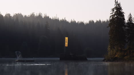 Lakefront-View-of-Somebody-Swimming-at-Caumasee-Lake-Switzerland-in-Early-Morning-in-Summer-Season,-Wild-Lakeside-Swiss-Nature-Landscape-Around