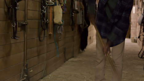 man in dark blue shirt cleaning the stable