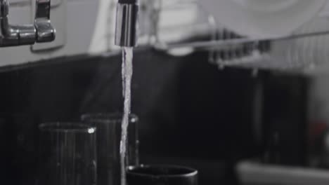 Cropped-view-of-woman-holding-dishware-in-hands,-washing-plate-under-water-in-sink,-putting-it-on-rack-to-dry