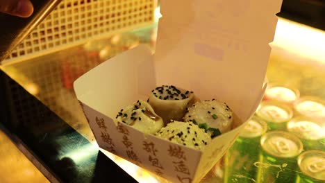 sauce being poured over fried buns in box