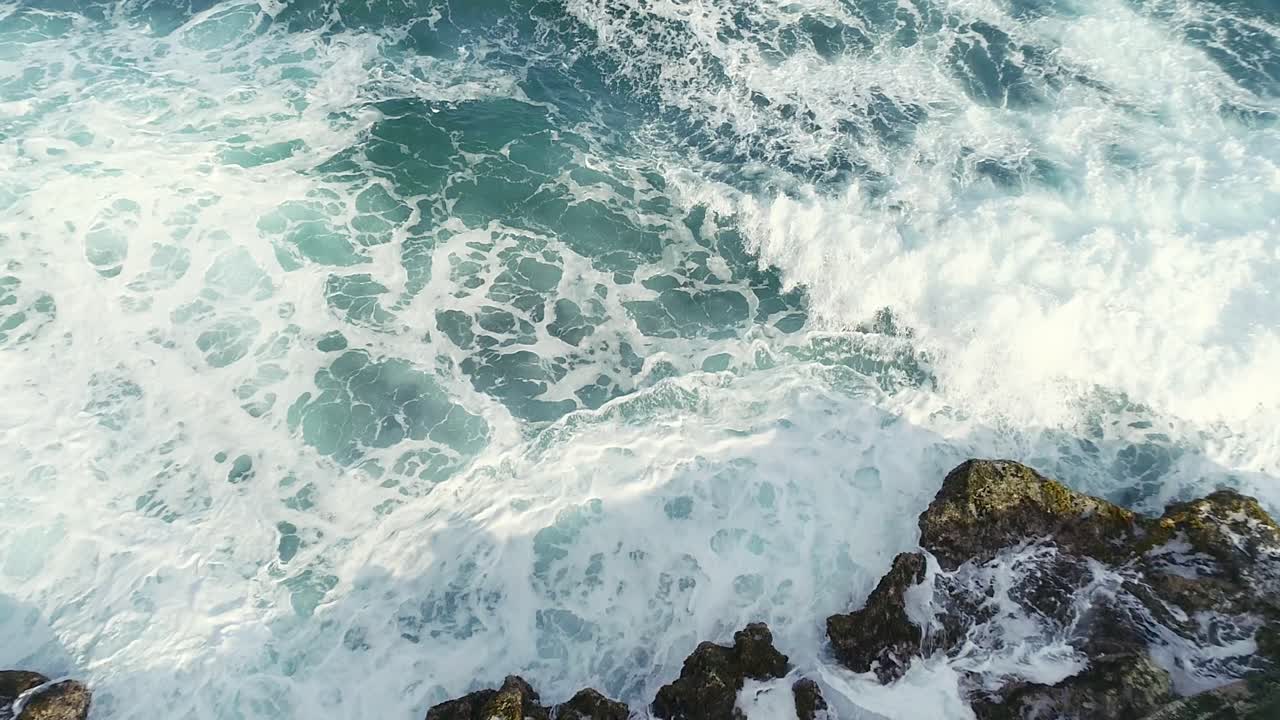 Ripresa aerea dall'alto all'indietro sopra le onde del mare che si infrangono sulla costa rocciosa vicino alla spiaggia di Najayo