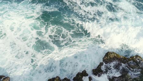 Aerial-top-down-backward-over-sea-waves-crashing-on-rocky-coast-near-Najayo-beach