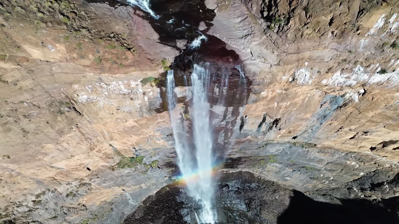 Vista aérea con dron de las Cataratas Maletsunyane en Lesoto, una poderosa cascada que se precipita por un alto acantilado de arenisca con un arcoíris formándose en la neblina de abajo
