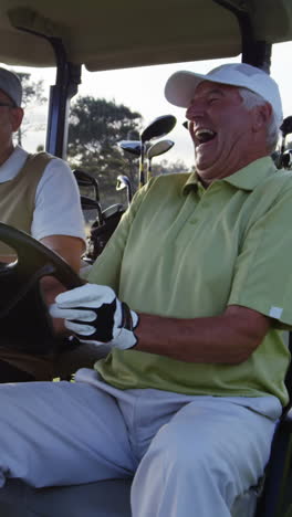 two golfers laughing together in their golf buggy