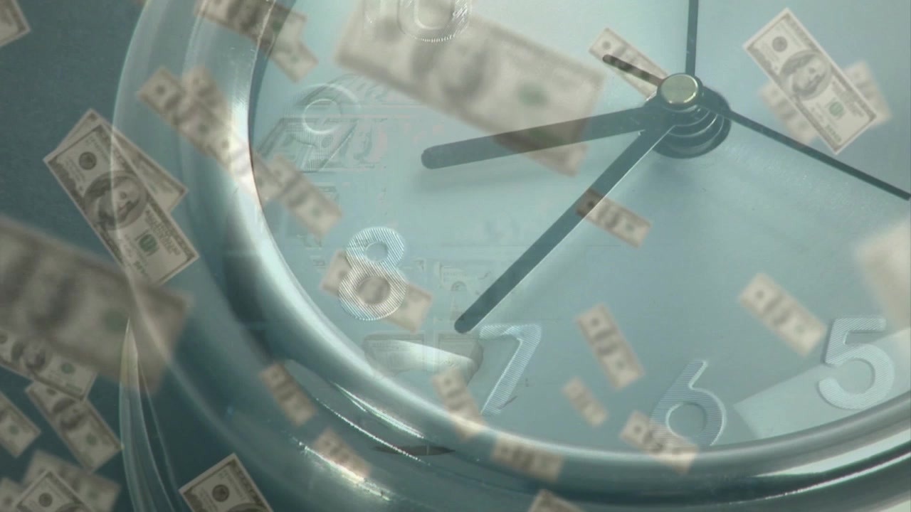Dinero en efectivo apareciendo sobre las manecillas de un reloj de metal que se mueven mientras los billetes flotan, y un globo emerge mostrando tiempo y dinero.