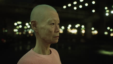 old asian woman in city at night