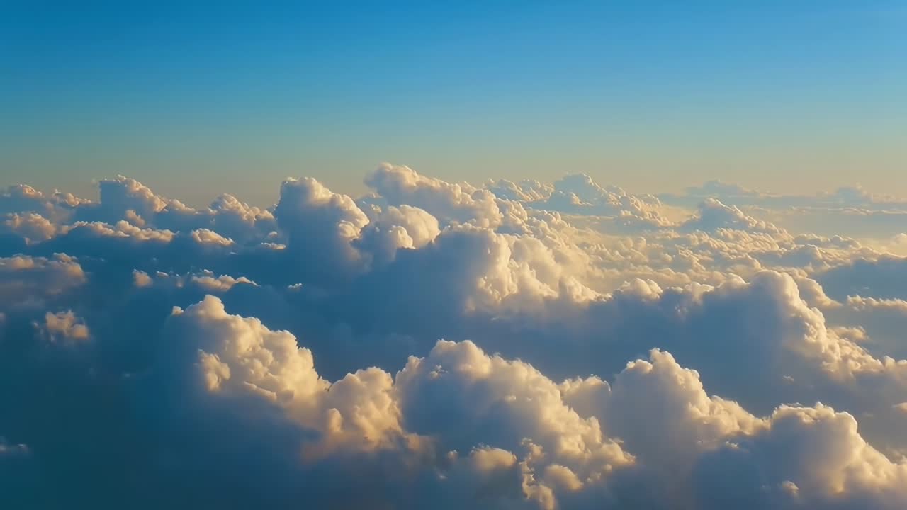 Aerial video view of fluffy clouds at sunset, capturing serene sky from above