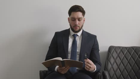 male candidate wearing suit in office checking notes before job interview 2