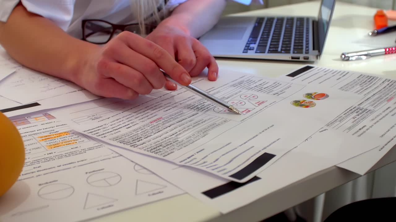 Hands review documents on desk with pen, paper charts, and detailed business planning notes, lively discussion