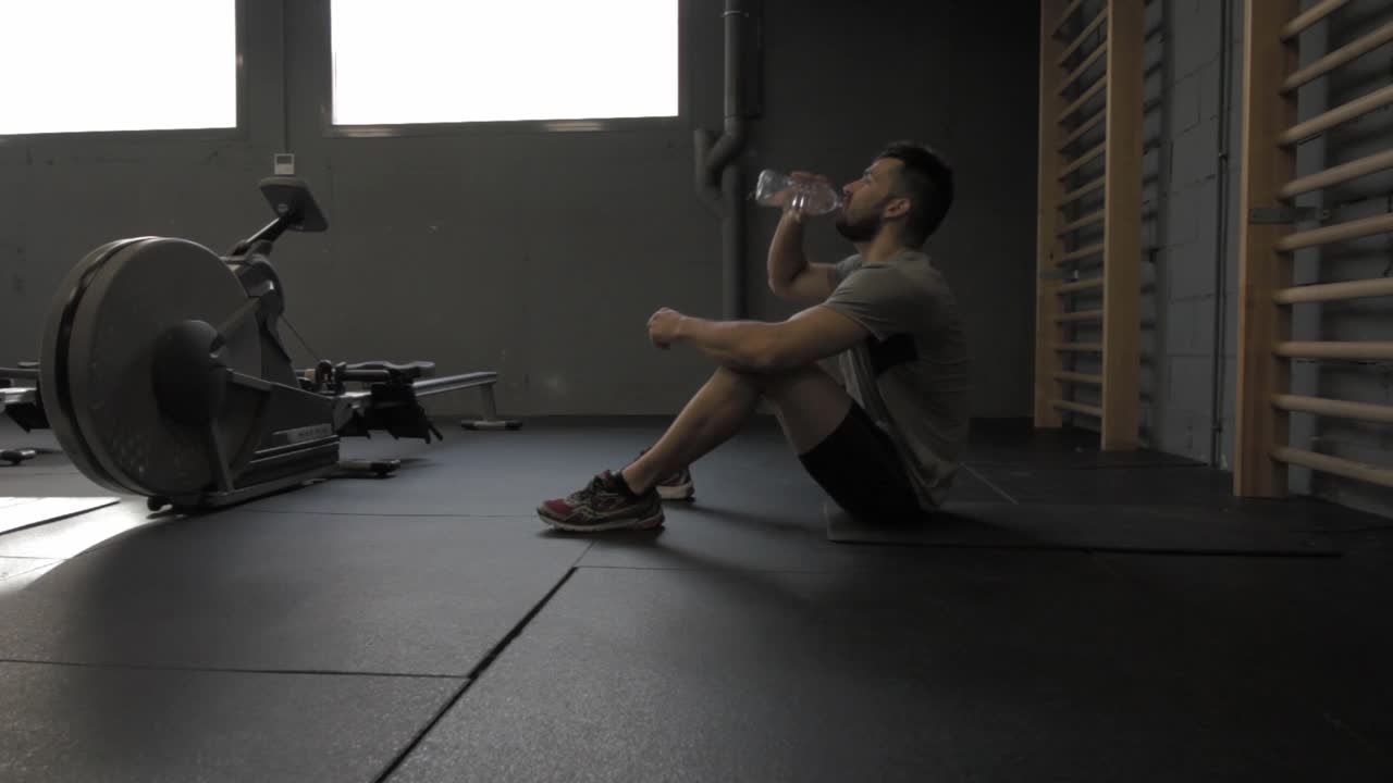 휴식을 취하고 물을 마시는 체육관에서 운동을 하는 젊은 운동 남자