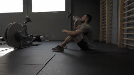 joven atlético haciendo ejercicio en el gimnasio descansando y bebiendo agua