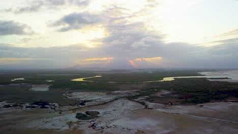 Drone-flying-at-approximately-high-above-large-open-area-moving-in-slow-arc-with-sunset-in-the-distance