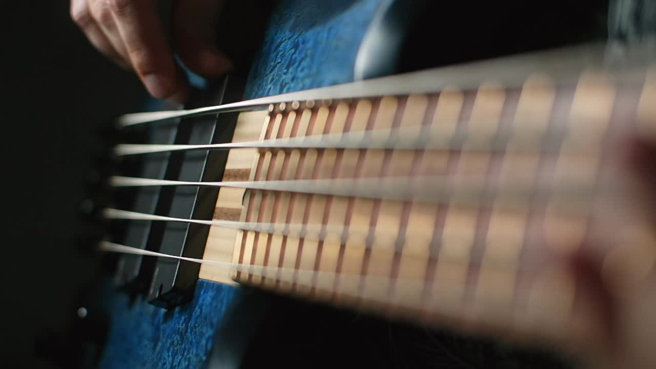 Close-up of a person playing a blue bass guitar
