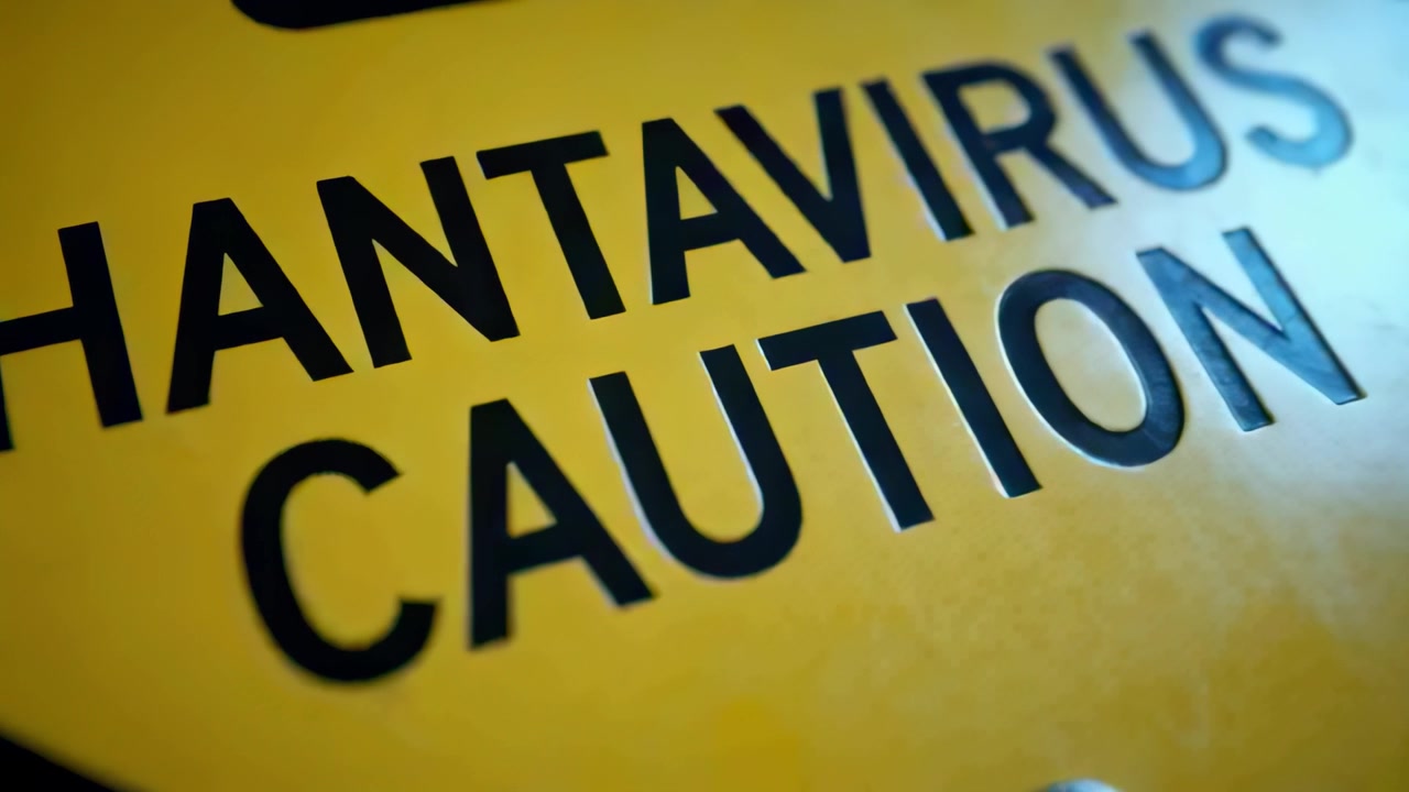 Panning camera revealing HANTAVIRUS CAUTION sign on panel showing metal screw black trim blue glow