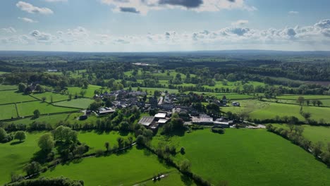 tynan village, county armagh, northern ireland, may 2023. drone slowly orbits counter clockwise in an aerial view of the village surrounded by rural green landscape with mix of sunny and cloudy skies.