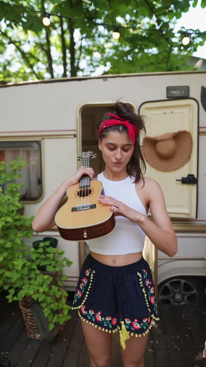 una mujer joven tocando el ukulele en una caravana