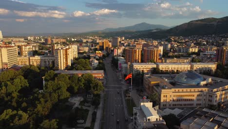 drone view over skopje cityscape at sunset with macedonia flag blowing - skopje, macedonia