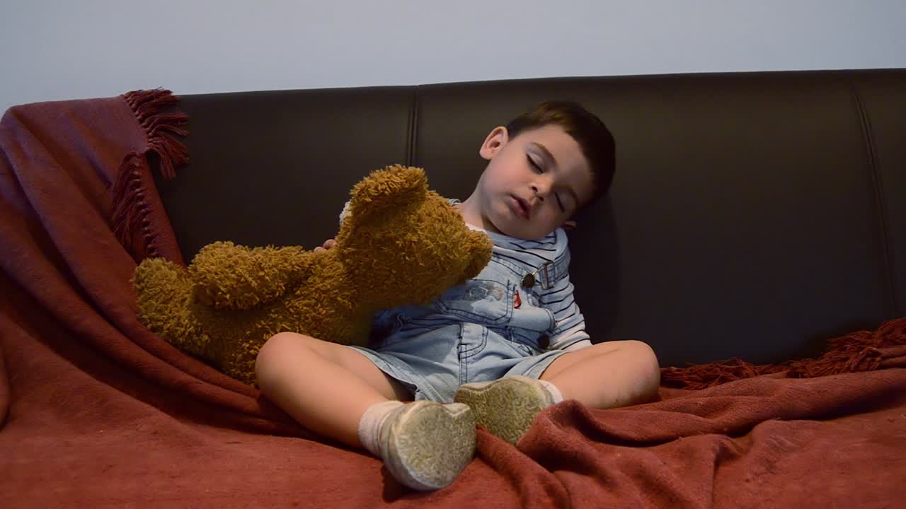 귀여운 피곤한 유아가 소파에서 잠이 들었습니다 - 재미있는 아기 얼굴 표정