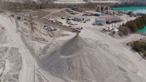 aerial drone footage slowly moving away from fast moving rocks falling off of a conveyor belt in a quarry.