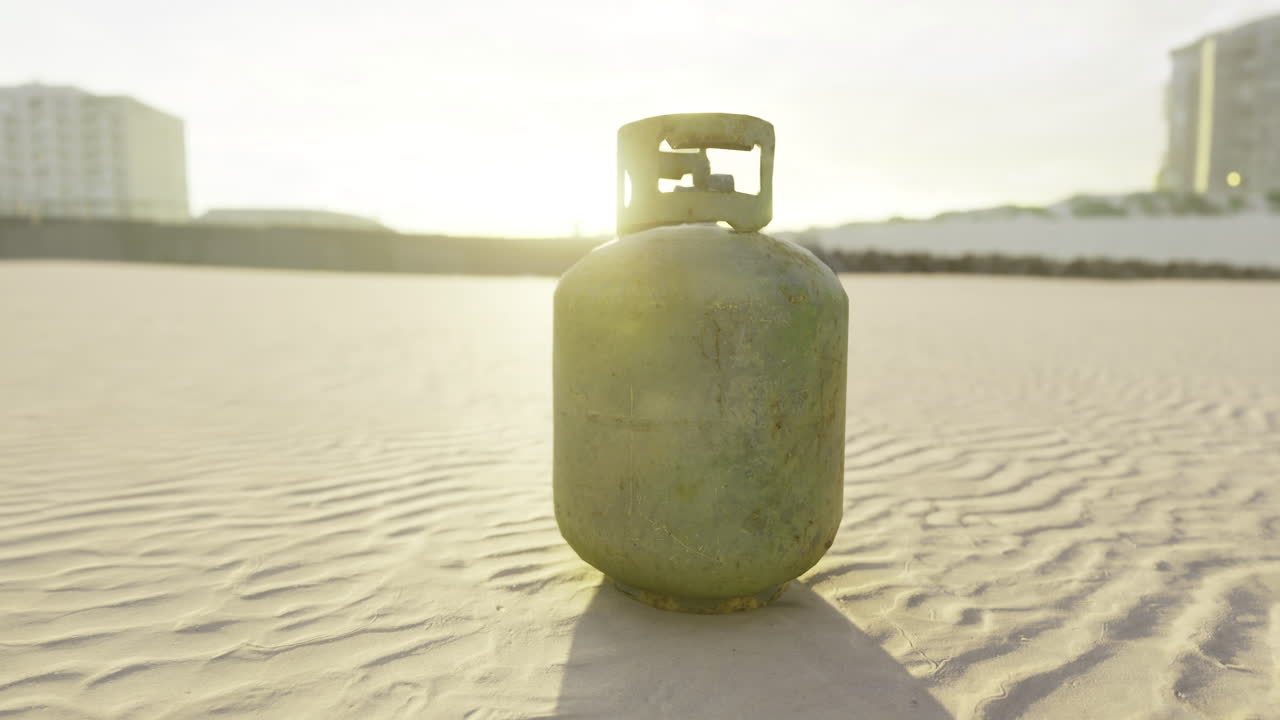 Gas cylinder resting on sandy shore during serene sunset