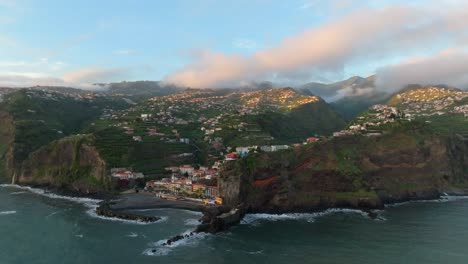 a pink-blue sky reveals the small town of ponta do sol in the distance