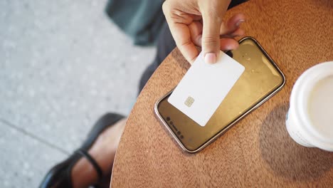 woman using a credit card and cellphone at a coffee shop