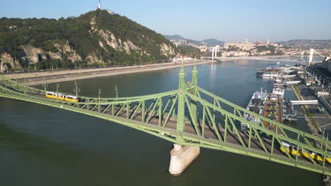 toma cinematográfica del puente de la libertad en budapest mientras los coches y los tranvías cruzan el río danubio